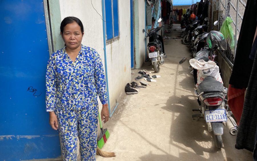 A woman stands in an alley way in Phnom Penh. There are motorcycles behind her.