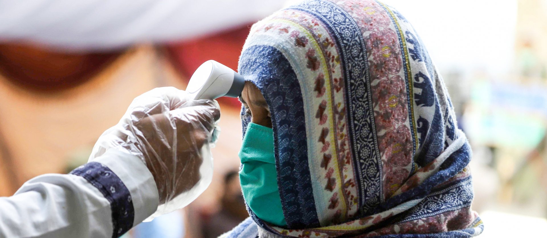 Woman in Pakistan getting her temperature checked on her forehead