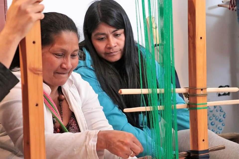 Two Awá women sitting at a loom weaving