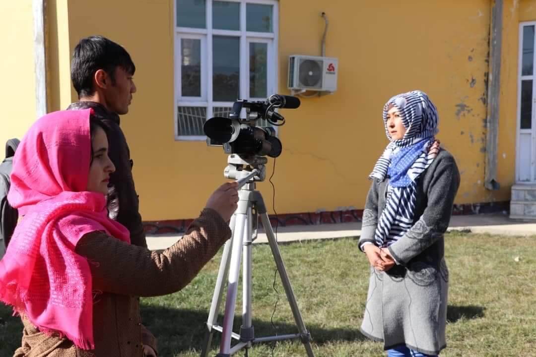 A man and a woman camera operator and a woman journalist film in Afghanistan.